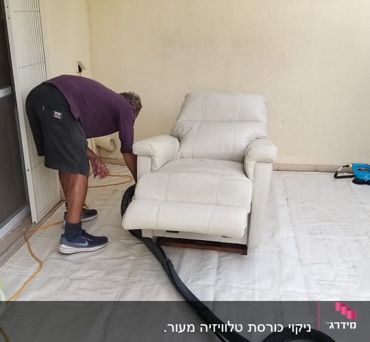 אדם מנקה כורסה עם שואב אבק ודלי מים